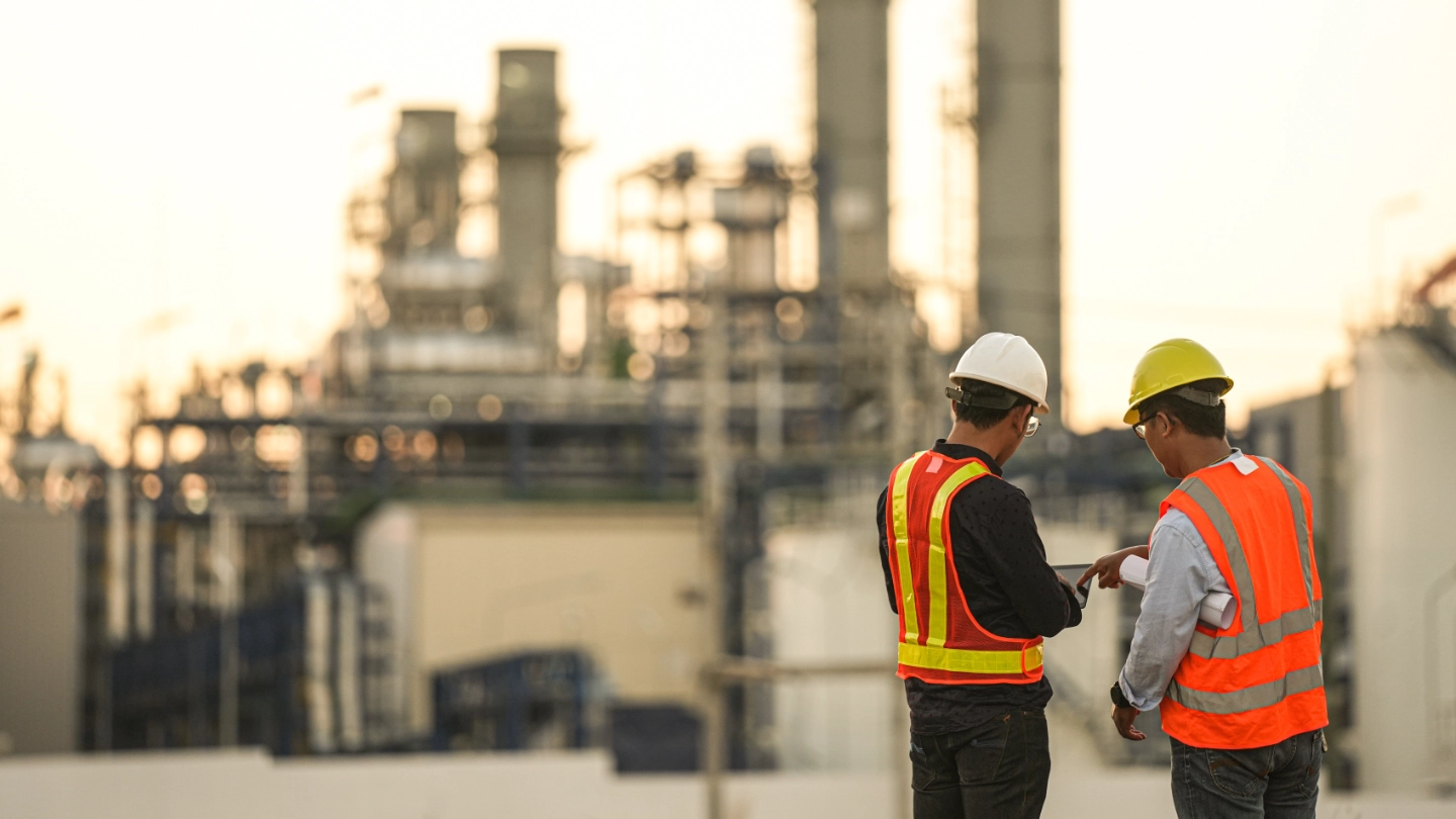 Two workers in front of a chemical plant Two workers in front of a chemical plant