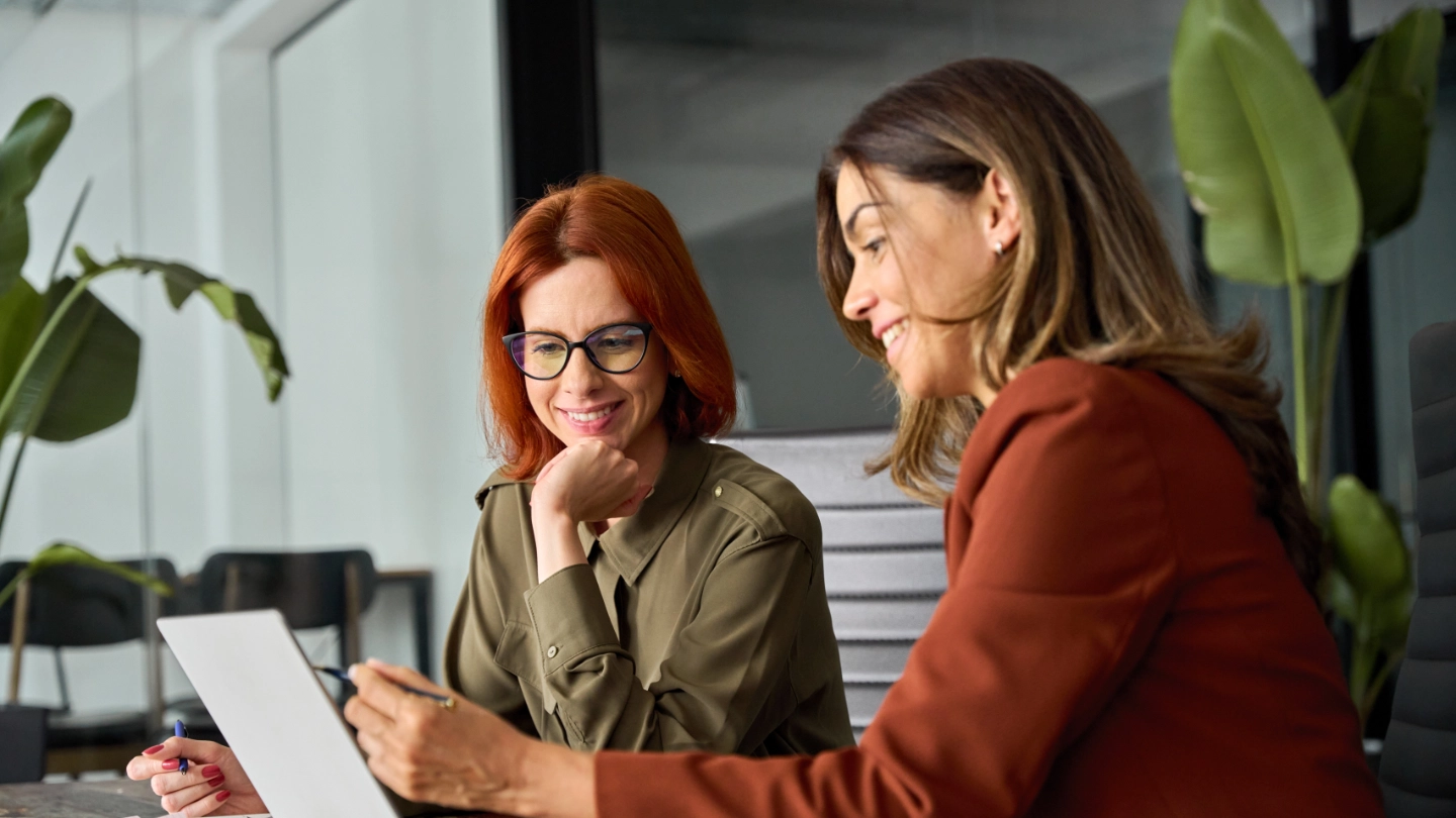 Two smiling young women reviewing work on a laptop Two smiling young women reviewing work on a laptop