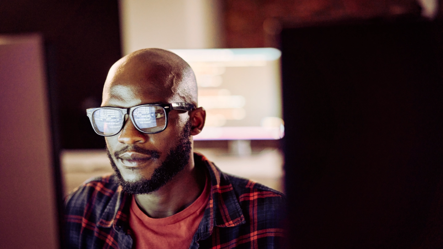 Male IT worker wearing glasses reflecting computer screen image