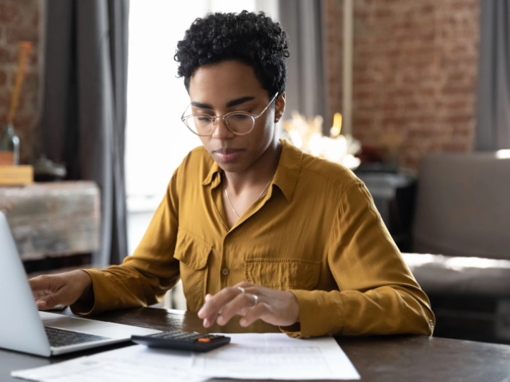 woman behind desk working with laptop and calculator image